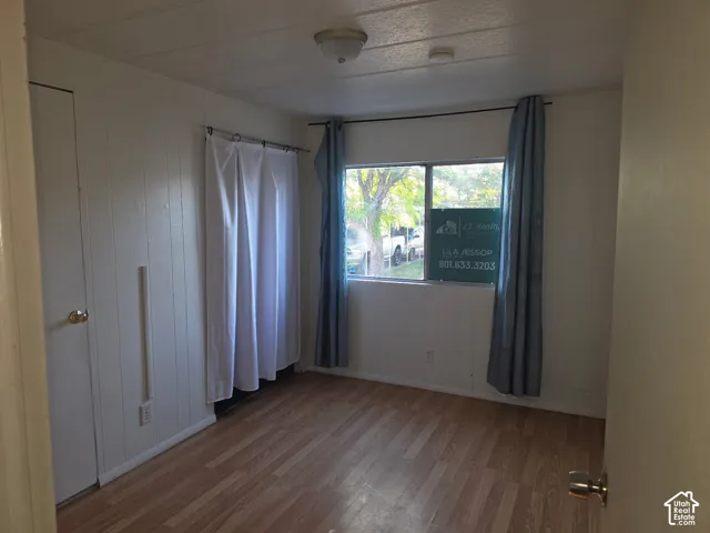 Wood-finish flooring with white paneled walls and a ceiling-mounted light fixture