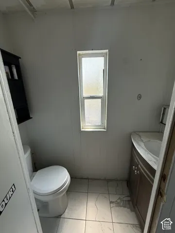 Compact bathroom featuring a ceramic toilet, pedestal sink, and tile flooring