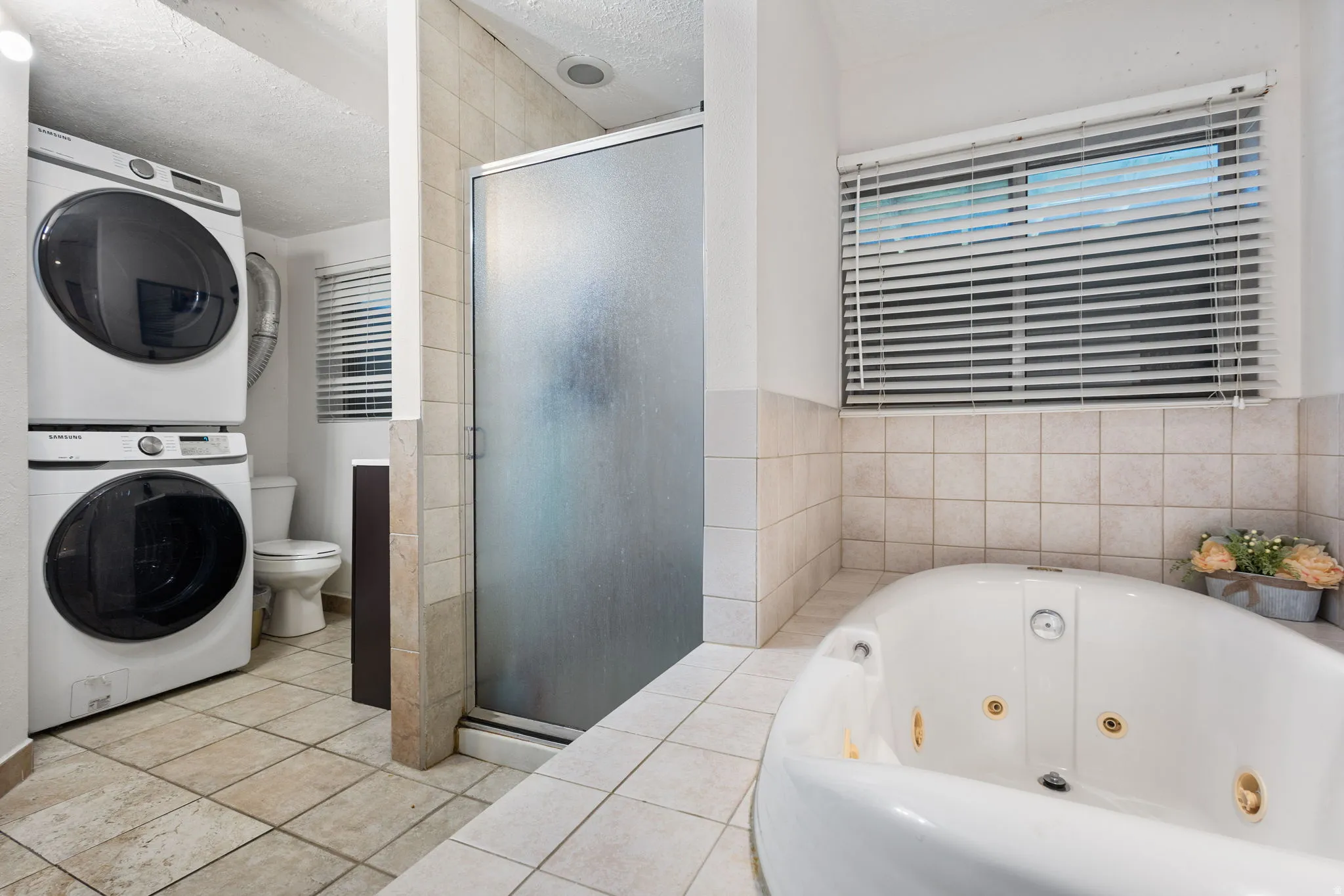Bathroom featuring a built-in jetted tub, a tiled shower enclosure with frosted glass, and ceramic tile flooring