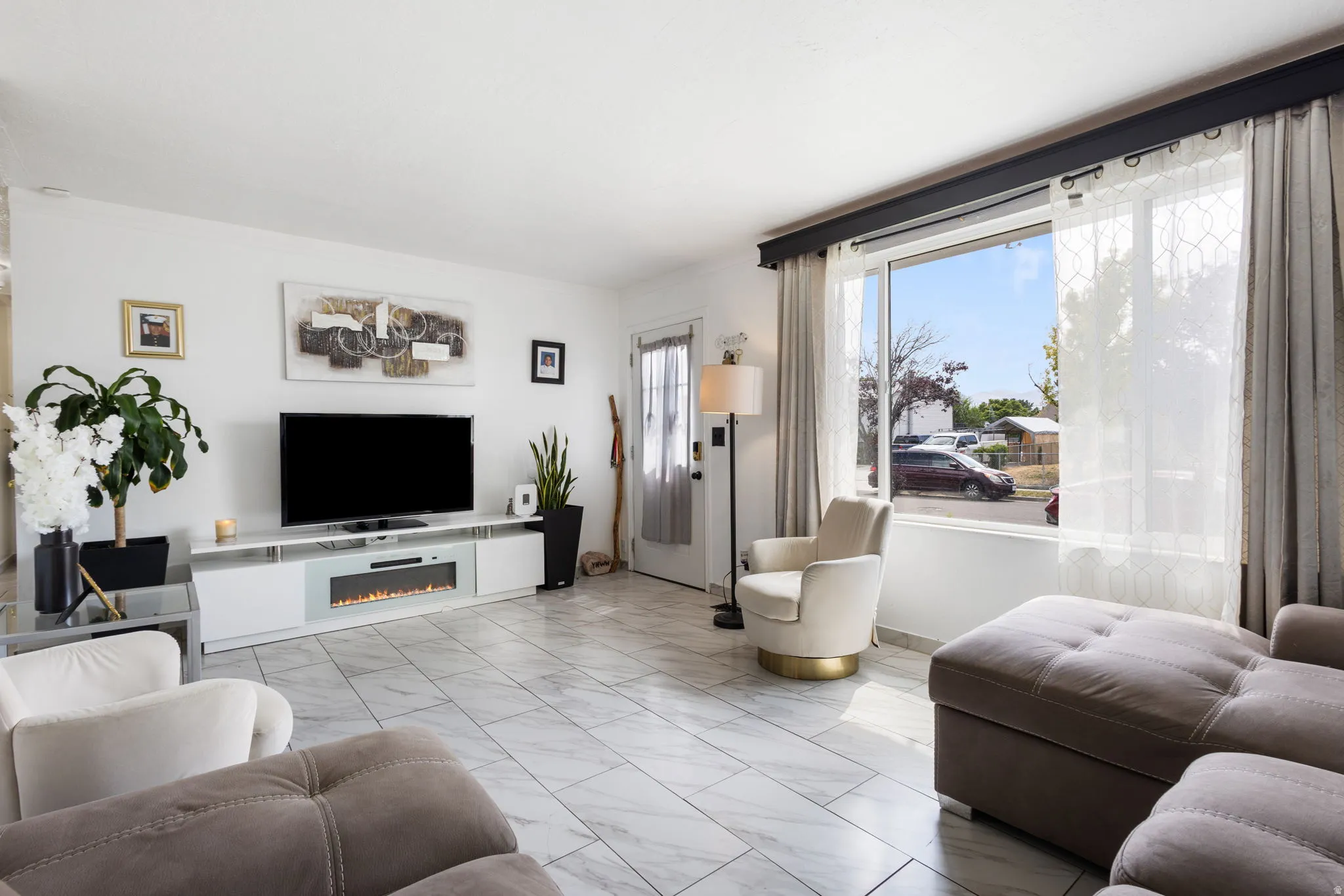 Open concept living area featuring large format white tile flooring and a built-in media console with an integrated electric fireplace