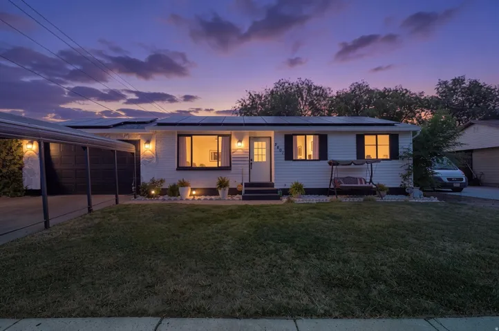 Ranch-style exterior featuring white siding with black trim, a covered carport, and multiple solar panels
