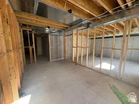 Unfinished basement space featuring exposed wooden framing, concrete flooring, and visible ductwork
