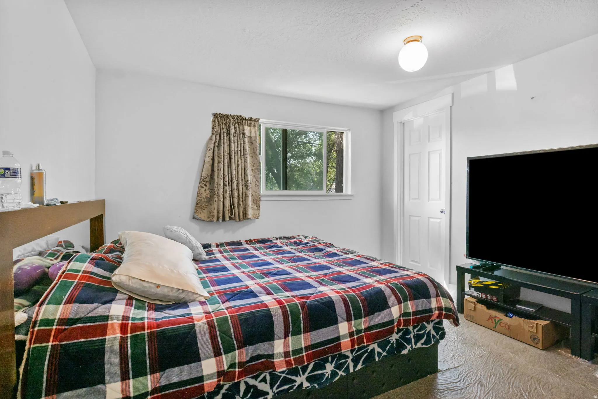 Room featuring light-toned walls, wood-finish flooring, a double-pane window, a white interior door, and a flush-mount ceiling light fixture