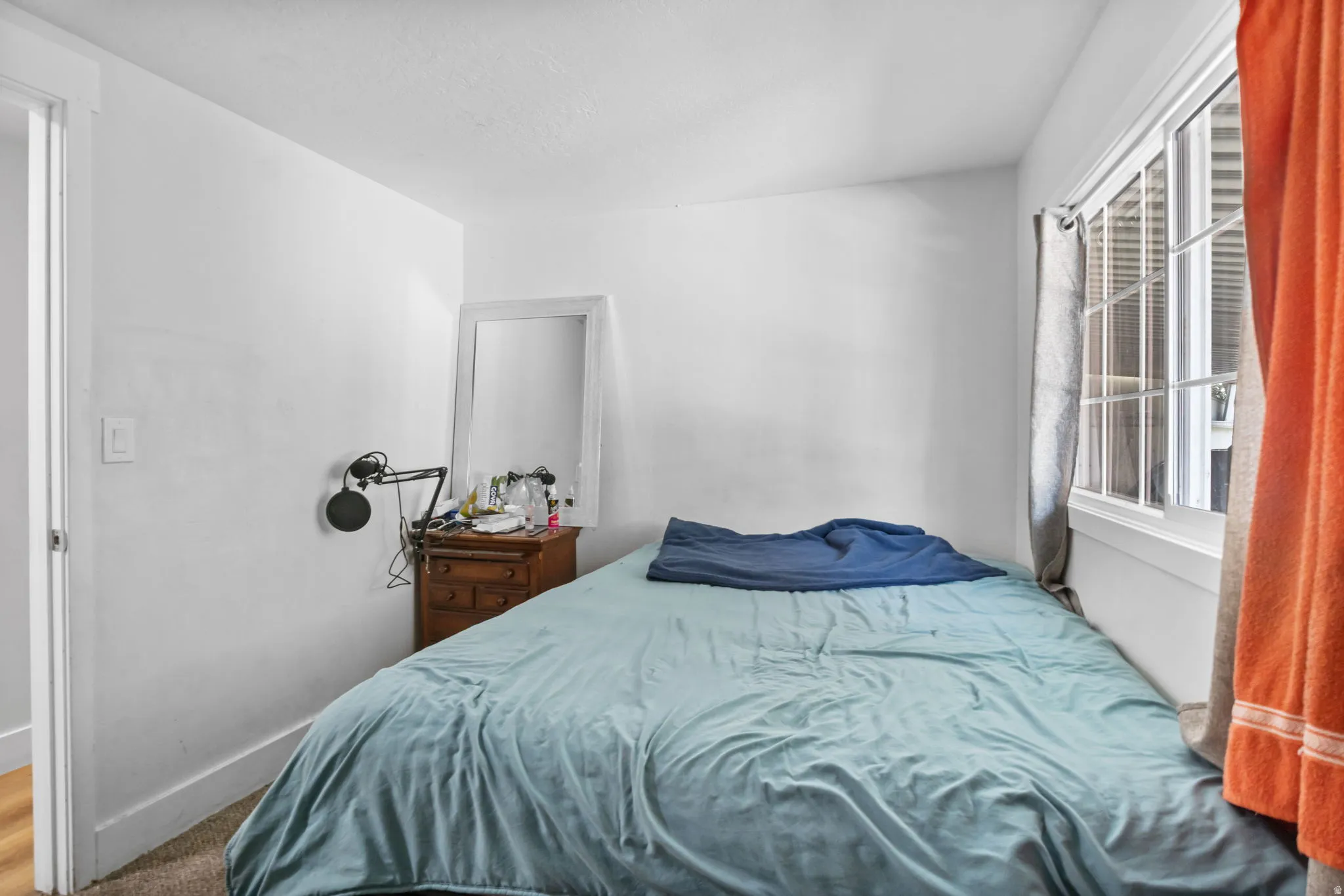 Room featuring white walls, a large window with white trim, and a doorway with white casing