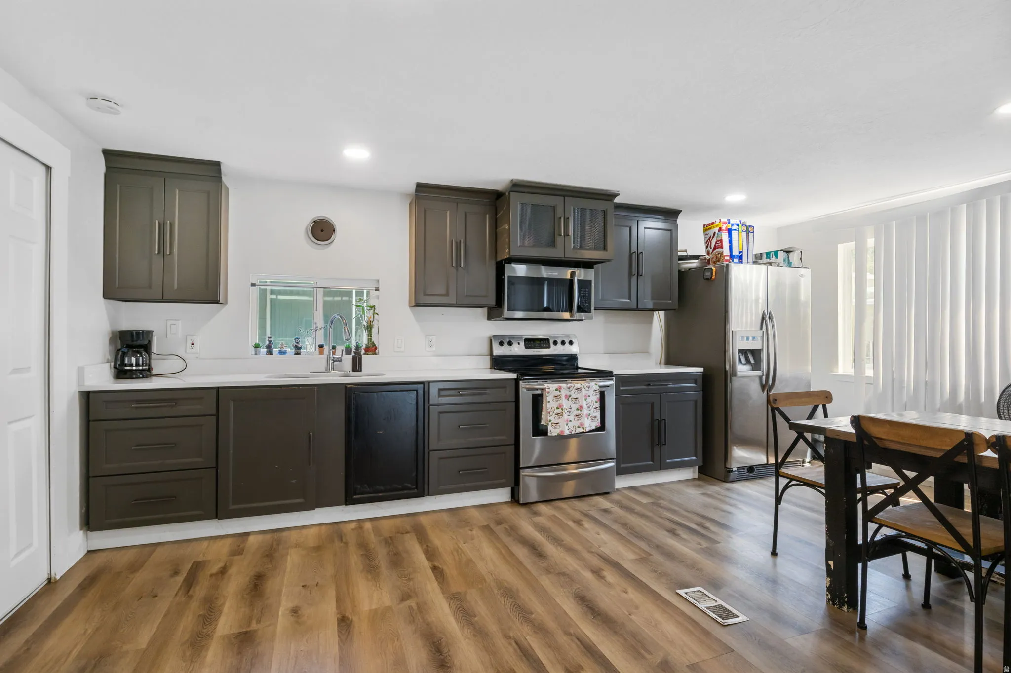 Kitchen featuring wood-finish flooring, dark cabinetry, light countertops, and stainless steel appliances