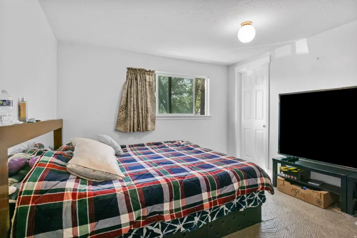 Room featuring light-toned walls, wood-finish flooring, a double-pane window, a white interior door, and a flush-mount ceiling light fixture