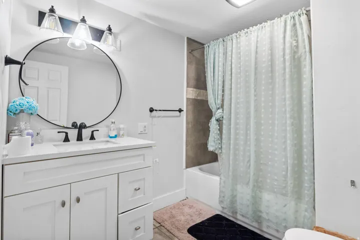 Modern bathroom featuring a white vanity with a rectangular sink and matte black faucet