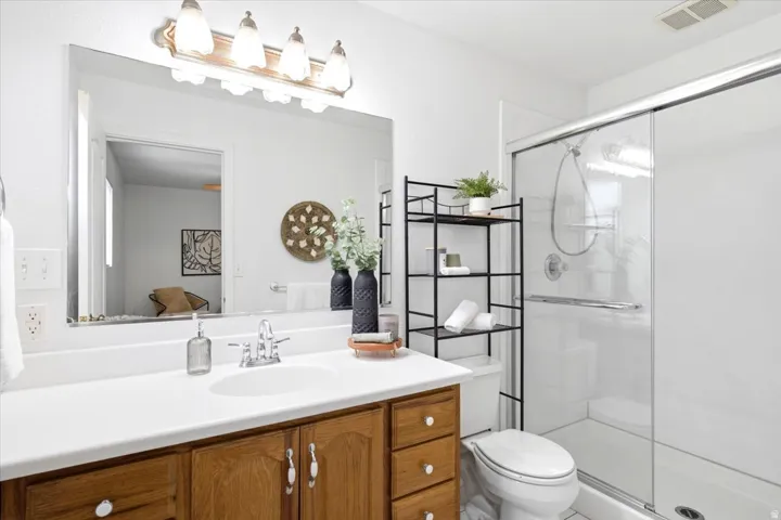 Bathroom featuring a single vanity with wood cabinetry, a white countertop, and a large mirror