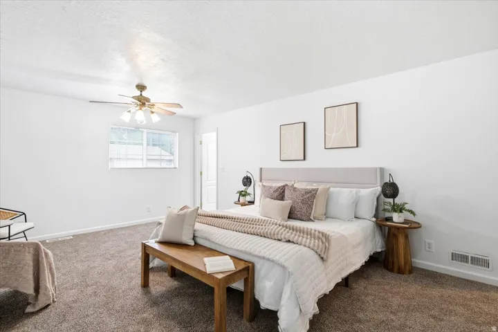 Spacious room featuring neutral carpeting, white walls, and a ceiling fan with integrated lighting