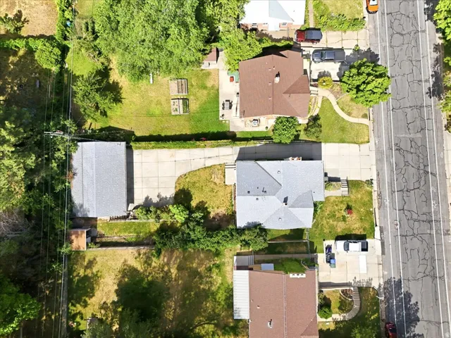 Aerial view featuring a residential property with a light gray shingle roof and an extensive concrete driveway