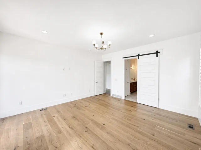 First floor primary bedroom with engineered wood flooring, recessed lighting