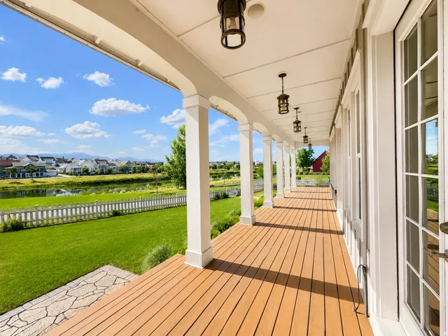 Expansive covered porch featuring wood-finish flooring, white architectural columns, and multiple hanging lantern-style fixtures