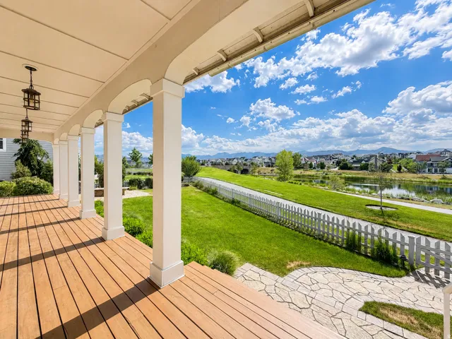 Expansive covered porch featuring wood-finish flooring, white columns with decorative arches, and two suspended lanterns