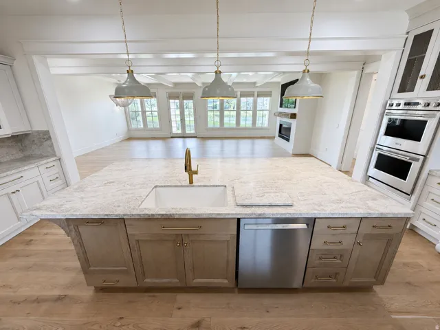 Expansive kitchen island featuring a built-in sink, gold-finish faucet, and integrated dishwasher