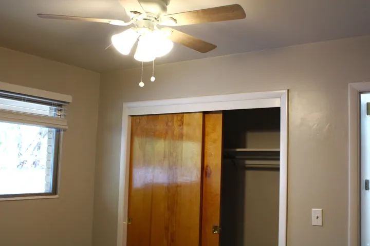 Room featuring a ceiling fan with integrated lighting, a window with horizontal blinds, and a closet with wood-finish sliding doors