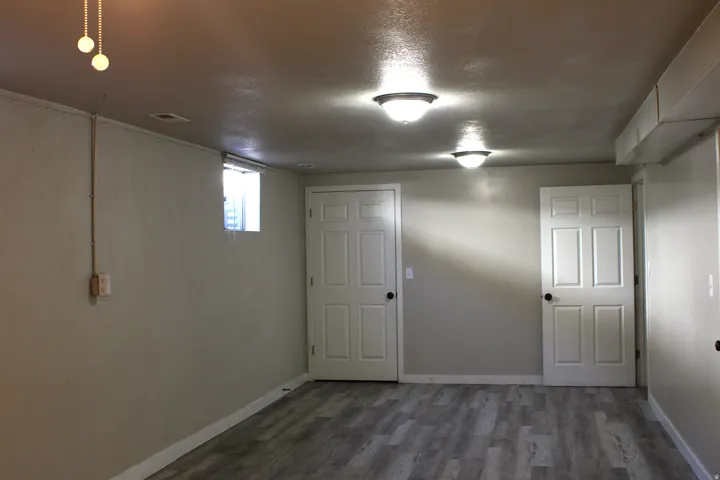 Spacious interior featuring wood-finish flooring, neutral-toned walls, multiple paneled doors, and ceiling-mounted light fixtures