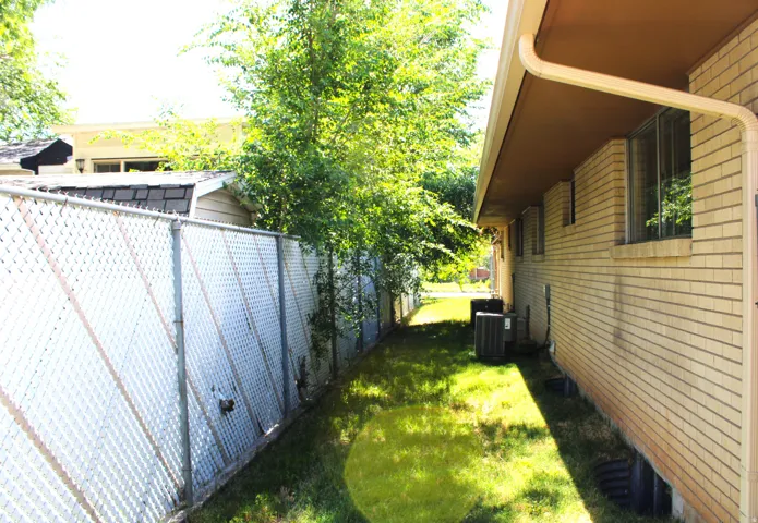 Side yard featuring mature trees and a chain-link fence