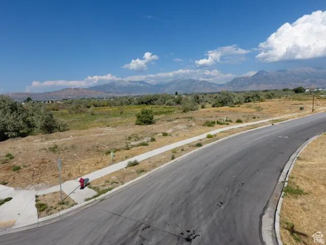 Expansive lot featuring a paved street, concrete sidewalks, and a mountain backdrop
