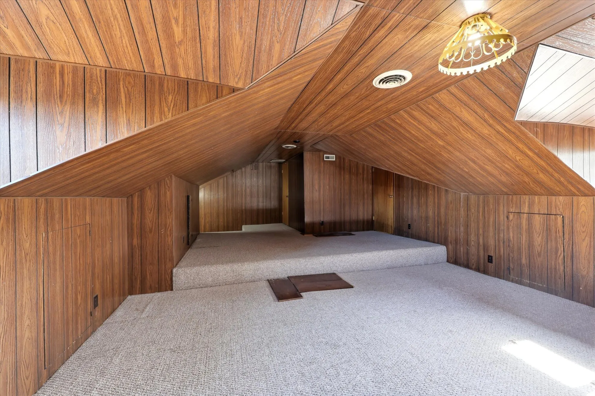 Carpeted room featuring wood-finish paneling on walls and vaulted ceilings