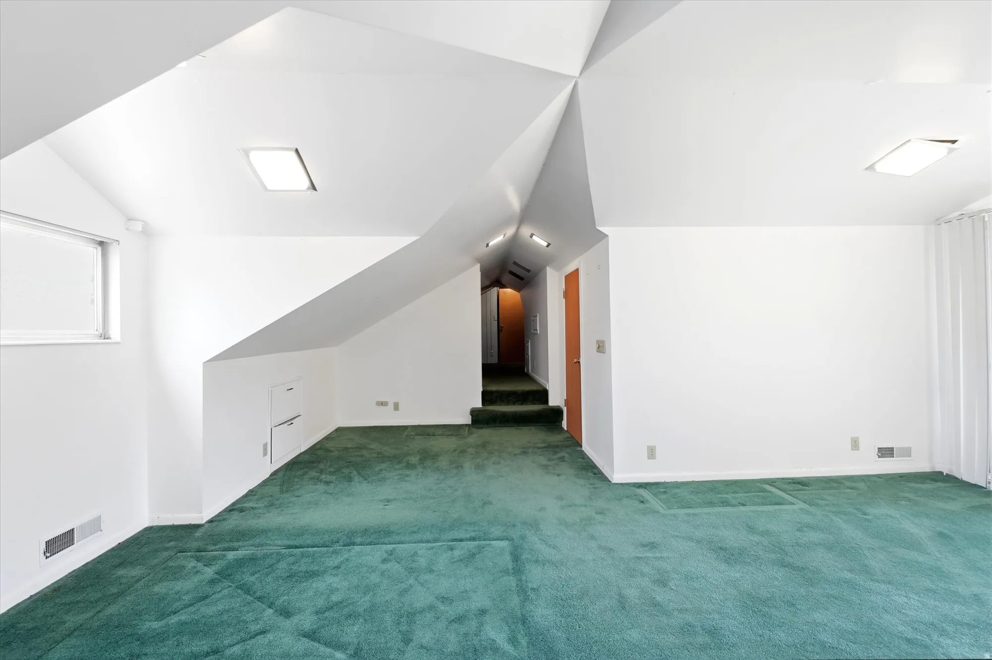Spacious finished attic space featuring sloped ceilings, recessed lighting, and green carpet flooring