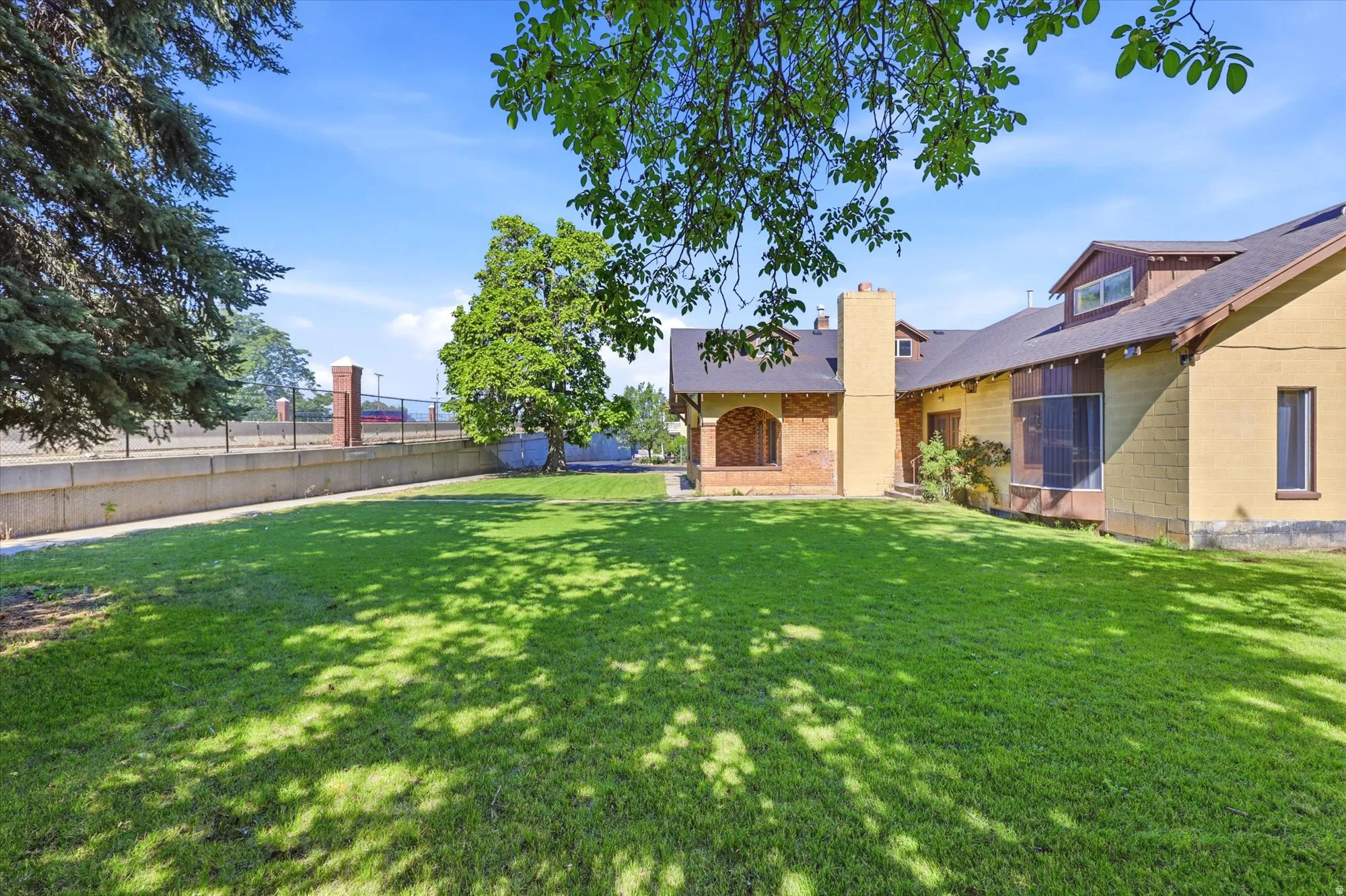 Expansive rear lawn with mature trees providing natural shade