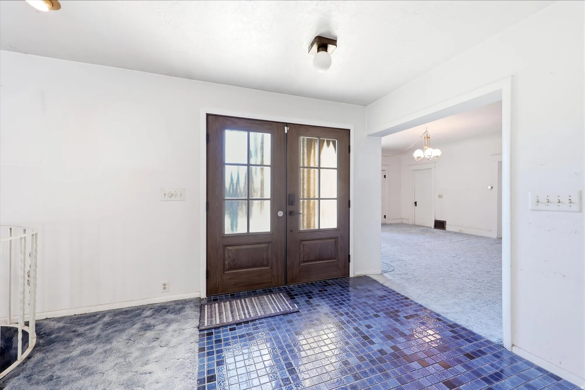 Foyer featuring double entry doors with divided lites, mosaic tile flooring, and a spiral staircase with white railing