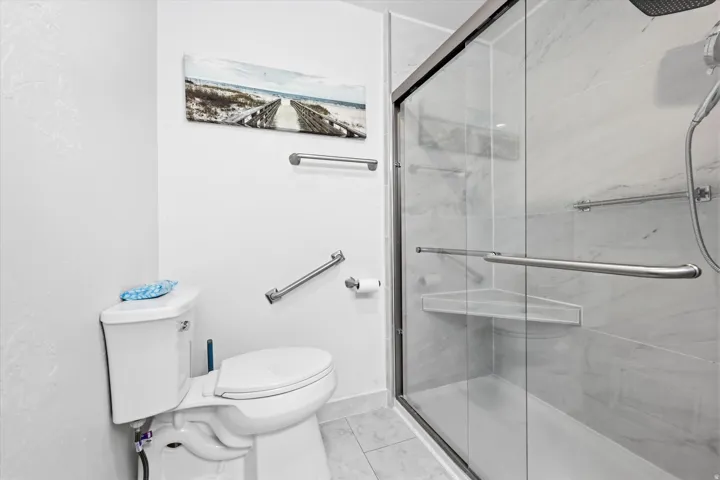 Contemporary bathroom featuring a spacious glass-enclosed shower with a built-in corner shelf and a sliding door