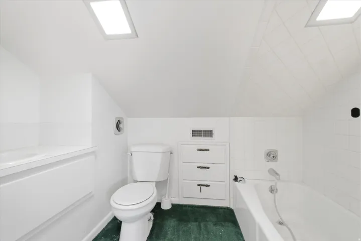 Bathroom featuring an integrated bathtub, toilet, and built-in storage drawers