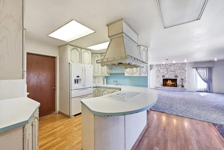Kitchen featuring a built-in cooktop island with a curved countertop, wood-finish flooring, and white cabinetry