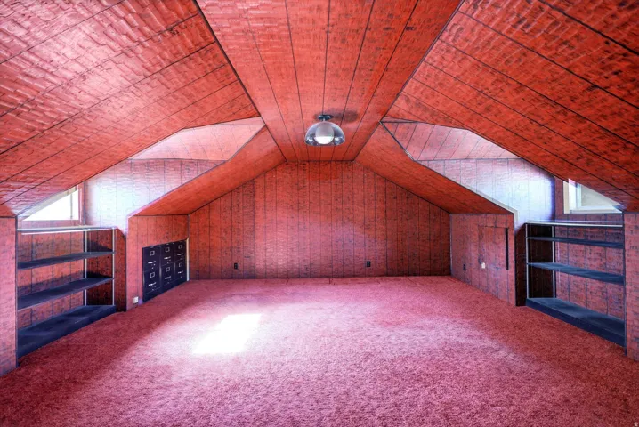 Attic room featuring sloped ceilings, paneling, and wall-to-wall carpeting