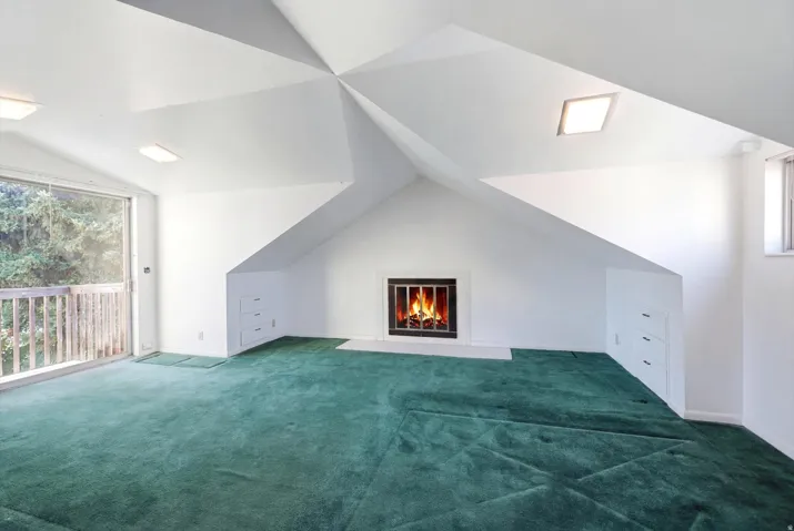 Spacious room featuring a fireplace with a black surround, white mantel, and hearth