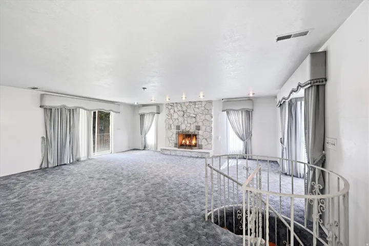 Spacious living area featuring a stone fireplace, recessed lighting, and sliding glass doors