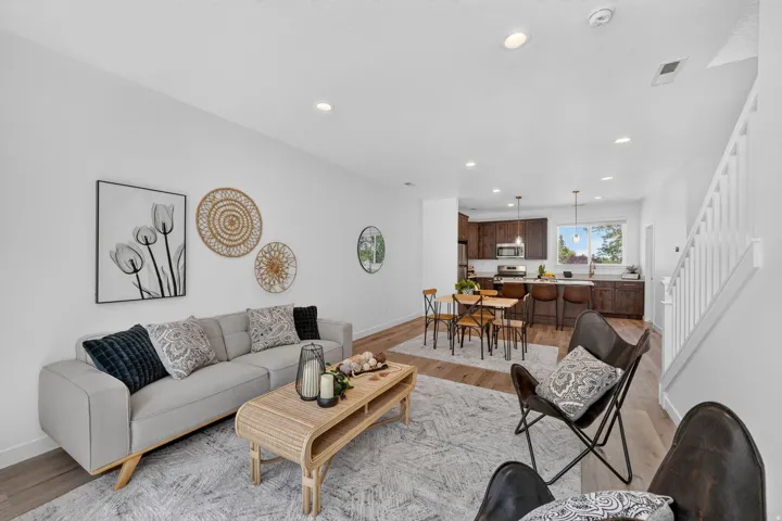 Open-concept living area featuring wood-finish flooring, recessed lighting, and a white baluster staircase