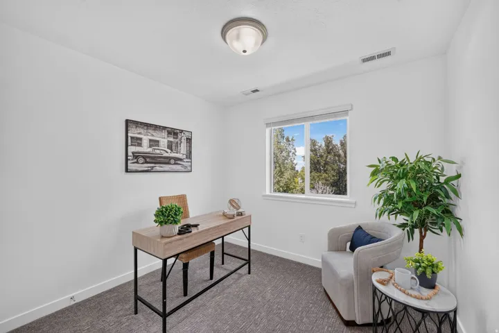 Bright room featuring neutral wall paint, a single window, and textured carpeting
