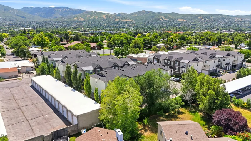 Modern townhome community featuring multi-story units with dark pitched roofs, light-colored facades, and prominent bay windows