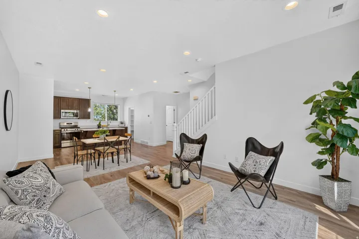 Open-concept living area with wood-finish flooring, recessed lighting, and a white baluster staircase