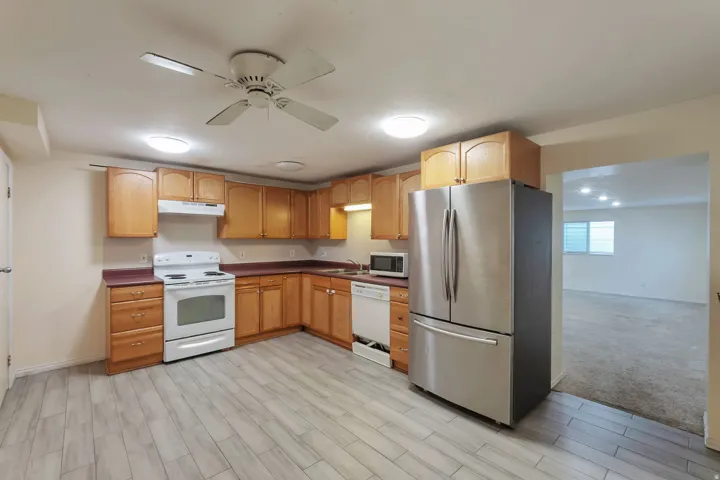 Kitchen featuring wood-finish cabinetry, white appliances, and stainless steel refrigerator