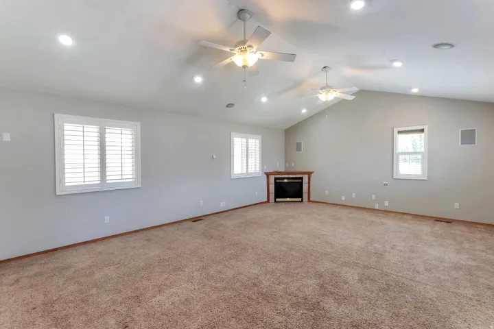 Spacious room featuring vaulted ceilings, recessed lighting, and two ceiling fans