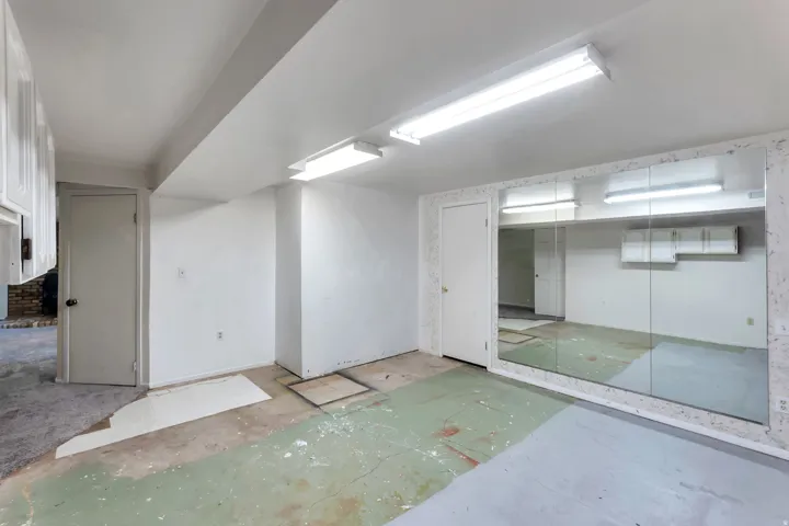 Expansive mirrored wall in a room with white walls and exposed ceiling beams