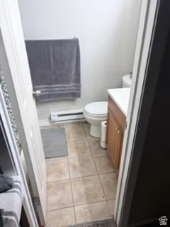 Compact bathroom featuring light-toned tile flooring, a white toilet, and a wood-finish vanity with a white countertop