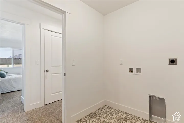 Dedicated laundry area featuring patterned floor tile, white wall finishes, and all necessary hookups for appliances