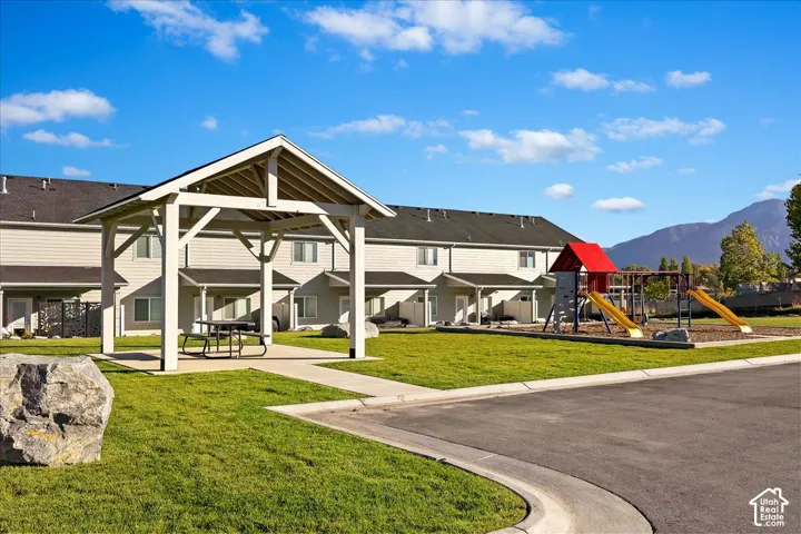 Community greenspace featuring a picnic gazebo, manicured lawn, and children's play structure with slides and climbing elements