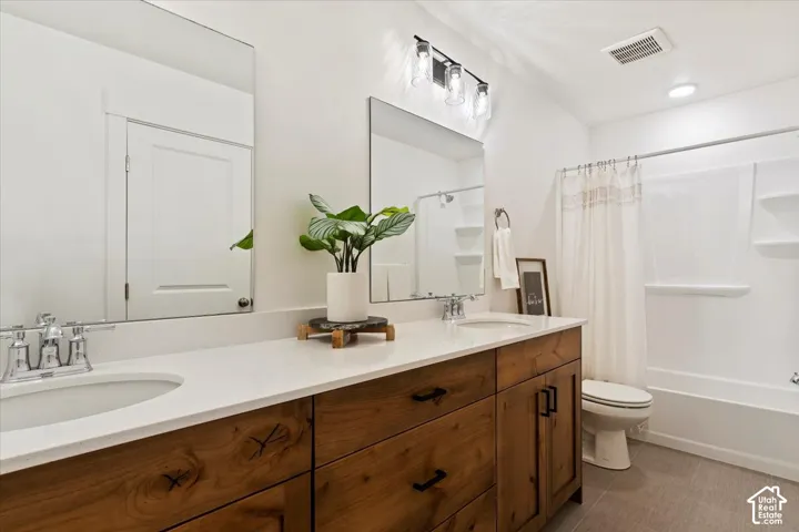 Double vanity with wood-finish cabinetry, white countertops, and undermount sinks