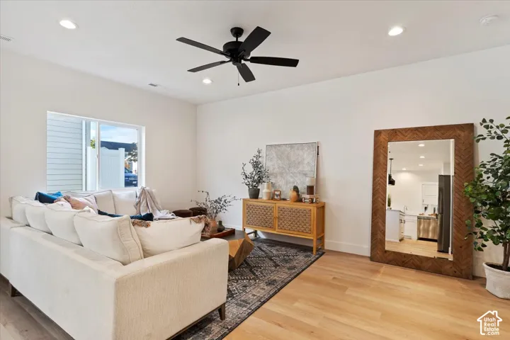 Bright living area featuring light wood-finish flooring, recessed lighting, and a modern ceiling fan