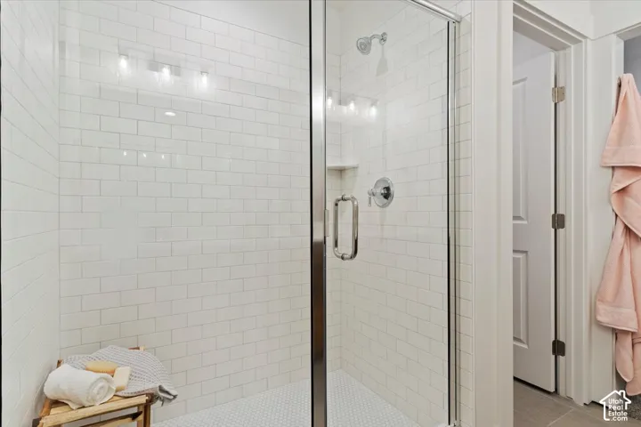 Glass-enclosed shower featuring white subway tile walls and a hexagonal tile floor