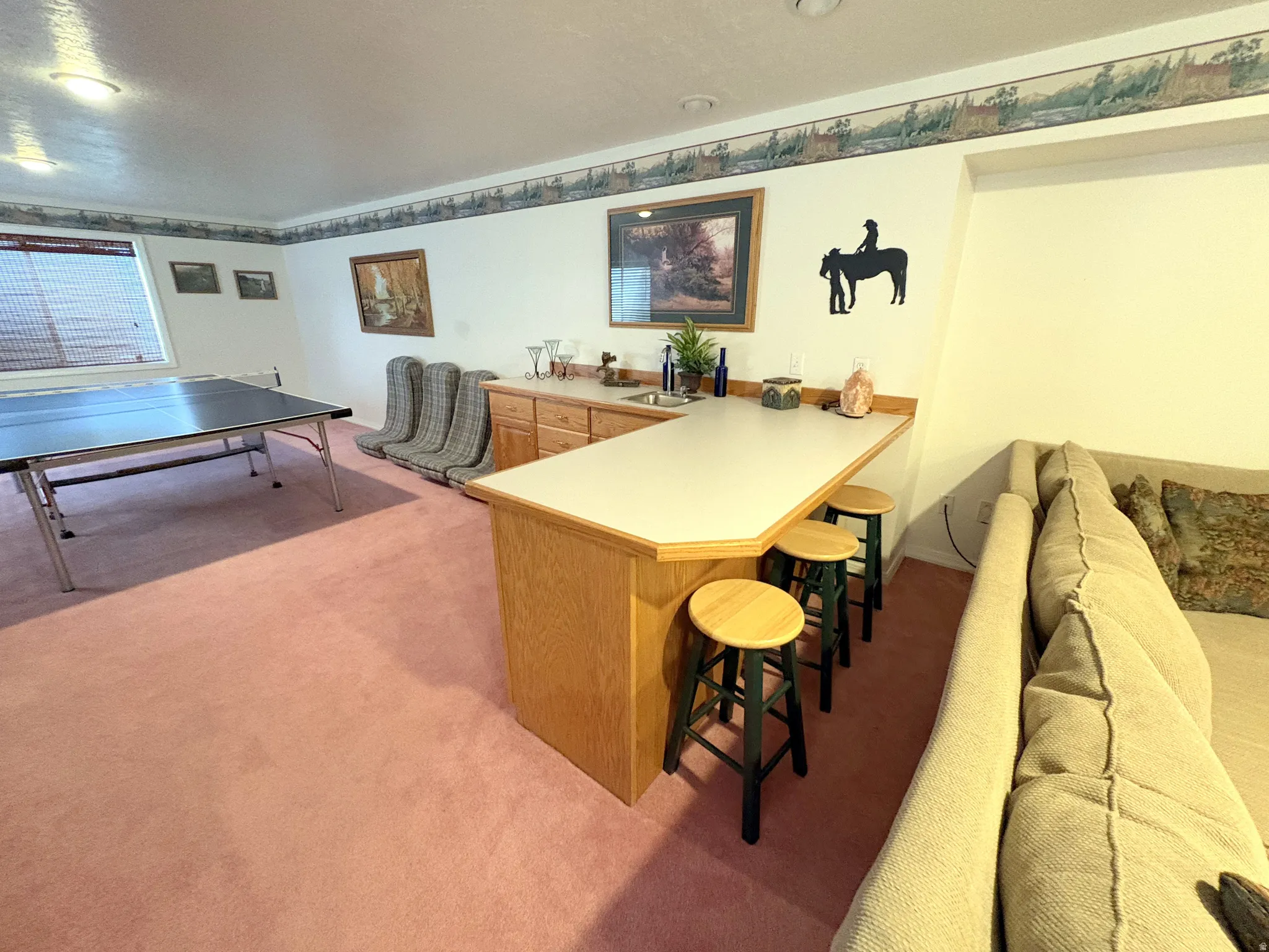 Recreation room featuring an integrated wet bar, wood-finish cabinetry, and a light-colored countertop