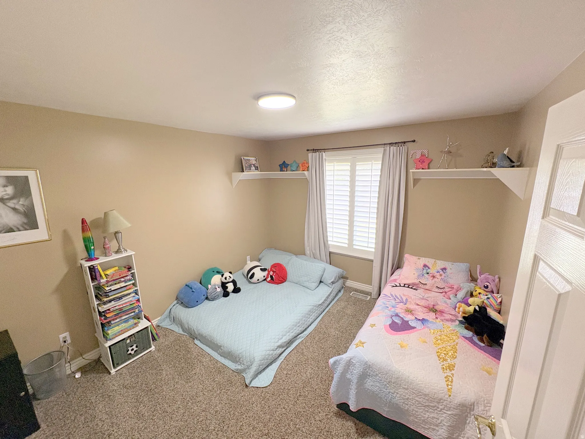 Room featuring neutral-toned walls, textured carpet flooring, and a flush-mount ceiling light