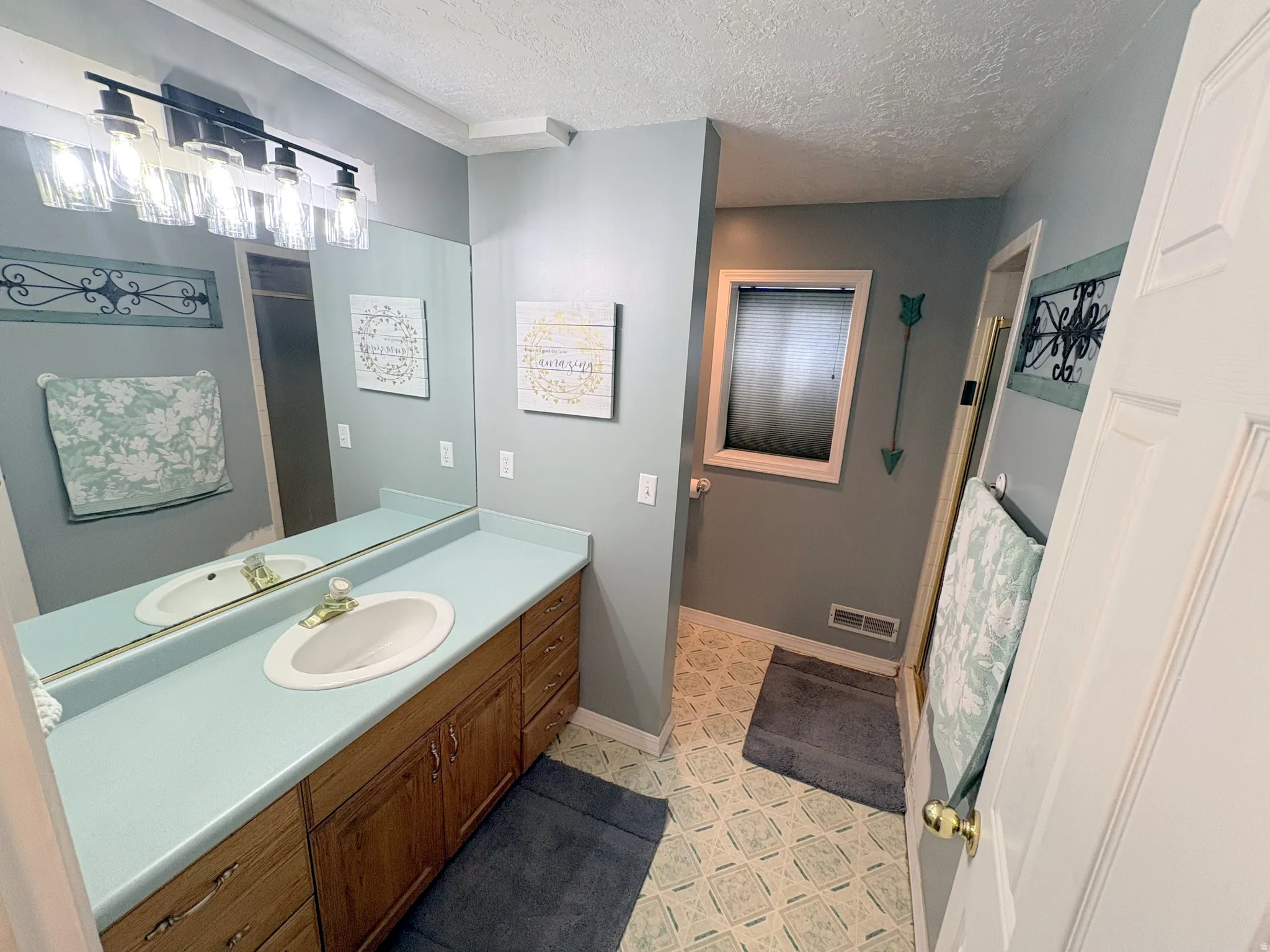 Double vanity with a light blue countertop and dual sinks, set on wood-finish cabinetry