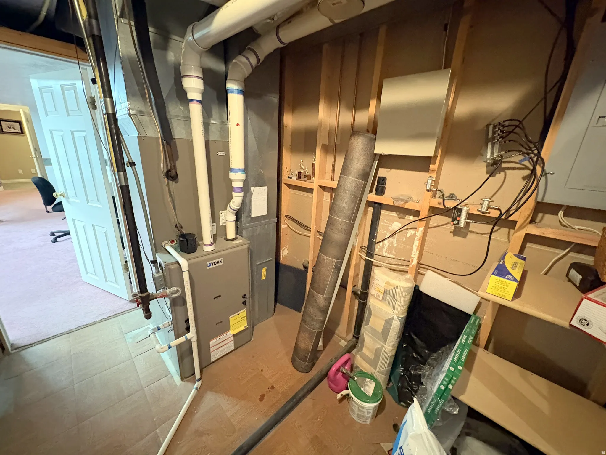 Utility area featuring a furnace unit, exposed stud framing, and electrical panels