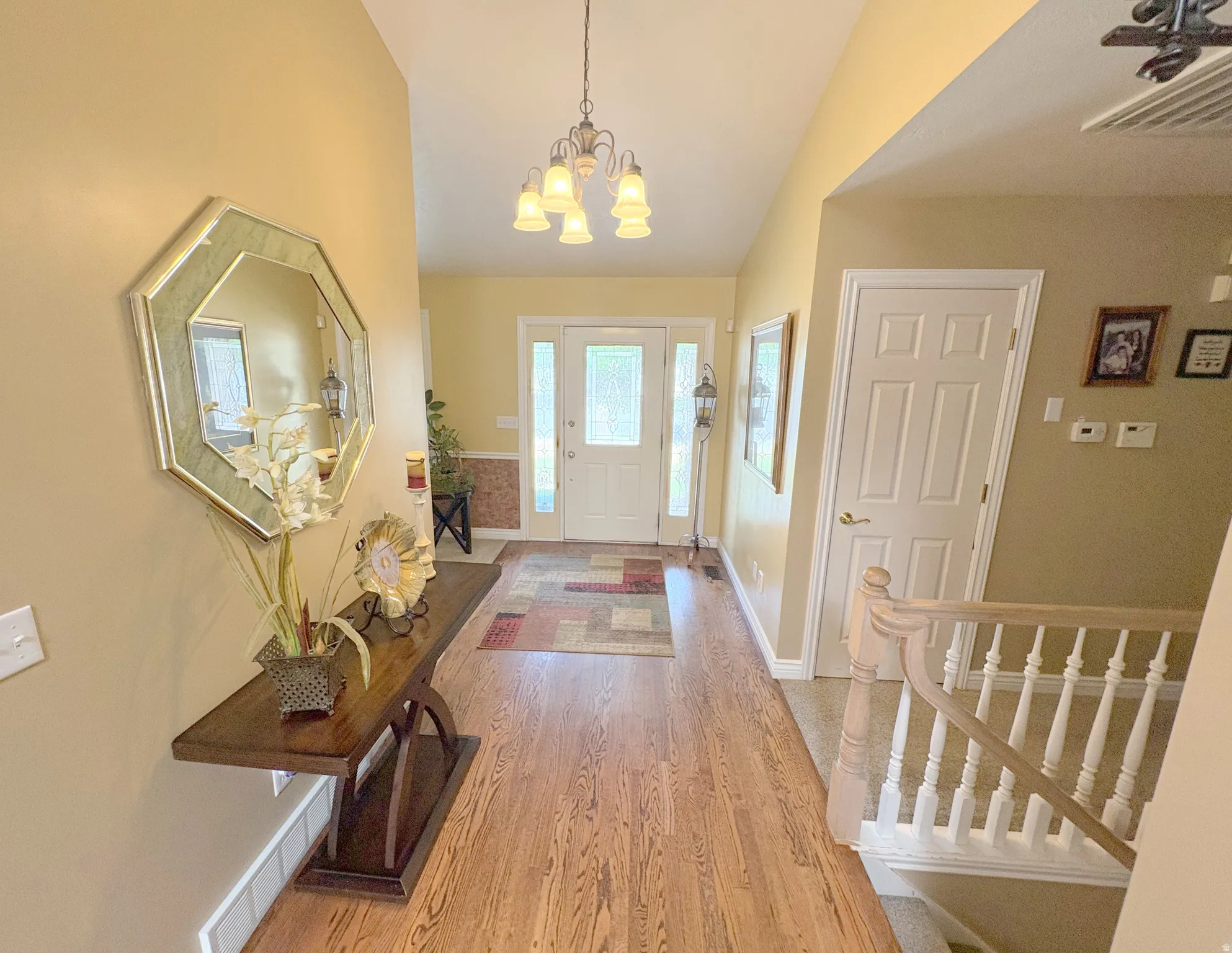 Entryway featuring wood-finish flooring, a vaulted ceiling, and an ornate chandelier